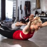 2 females are doing supermans at the gym.