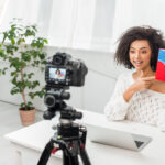 selective focus of happy african american influencer in braces pointing with finger at colorful box
