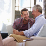 Adult Son Helping Senior Father With Computer At Home